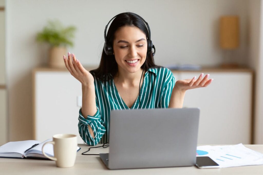 Online teacher working from home, using a laptop and headphones for a video call.