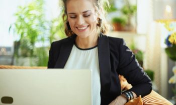 A woman using a laptop at home to search for remote jobs on a staffing agency website.