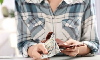 A woman holding an open wallet and cash.