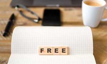 The word "free" spelled out with wooden blocks on a computer desk.