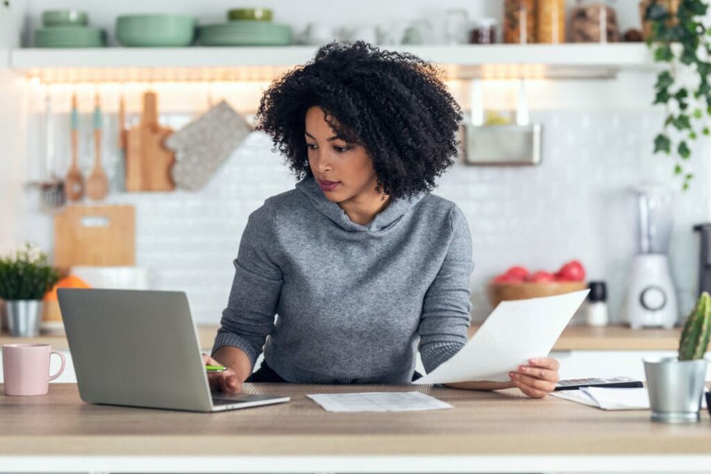 A woman working from home on a laptop in her kitchen.