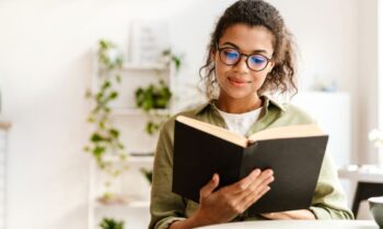 A woman business owner, sitting at a desk, reading a book.