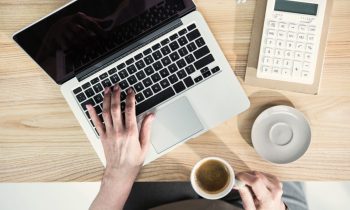 A freelancer working from home office and using a laptop to send an invoice.