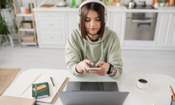 A woman working at home, sitting at her kitchen table and using her phone.