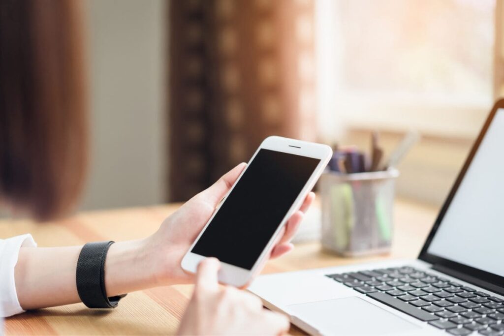 A woman working from home on a laptop and using a phone.