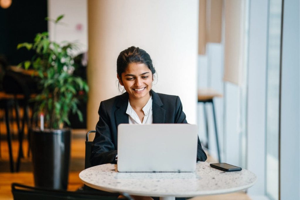 A woman paralegal working remotely from a cafe on her laptop.