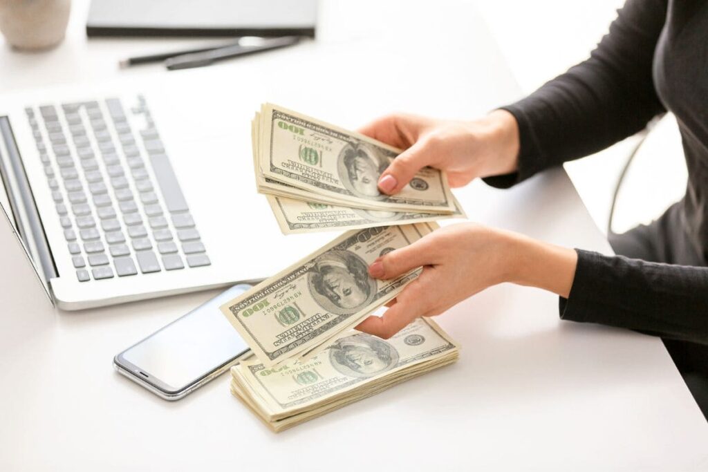 A woman sitting at her home office desk, counting cash.