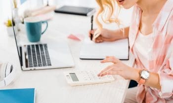 Woman sitting in home office, using a calculator and working on a budget