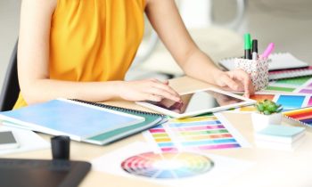 A woman working from home as a graphic designer, using a tablet to create graphics with Canva.