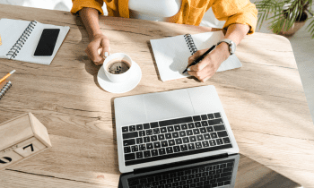 Woman drinking coffee writing in her notebook