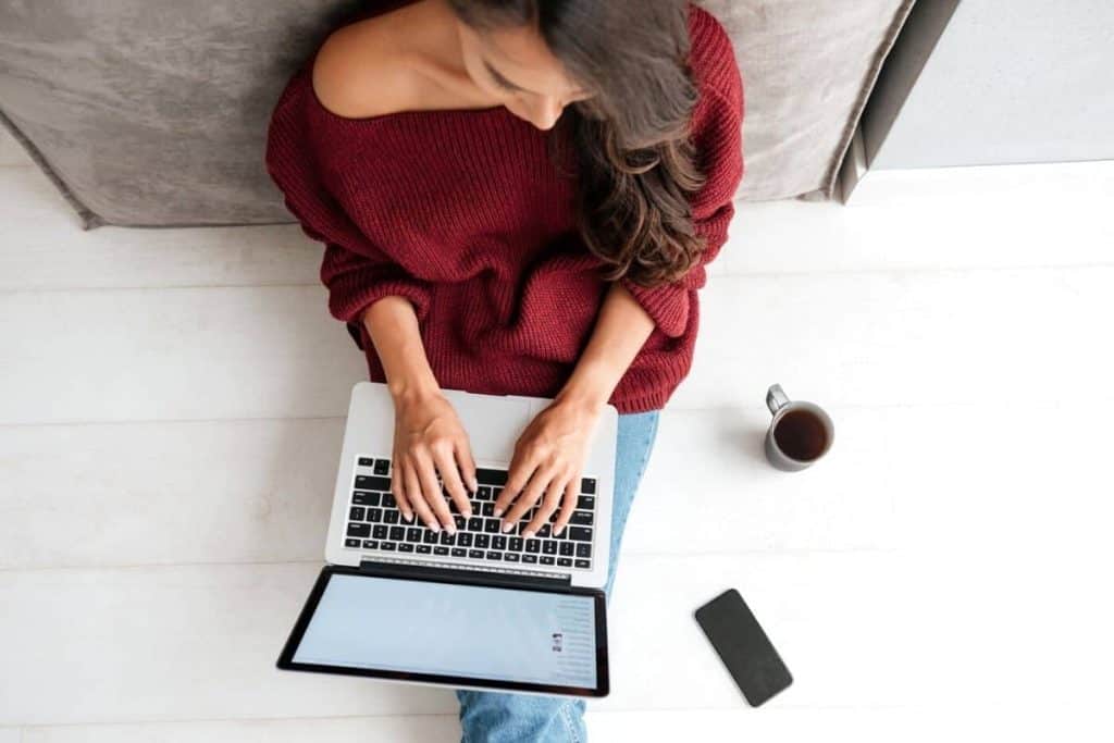 Woman with anxiety sitting on the floor and working from home on a laptop.