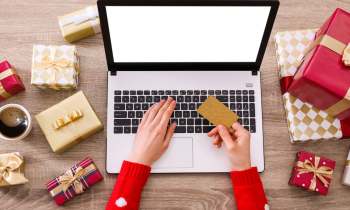 Woman looking at Black Friday Deals online surrounded by Christmas gifts