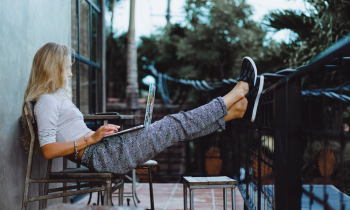 Woman working on her laptop on a balcony with her feet propped up