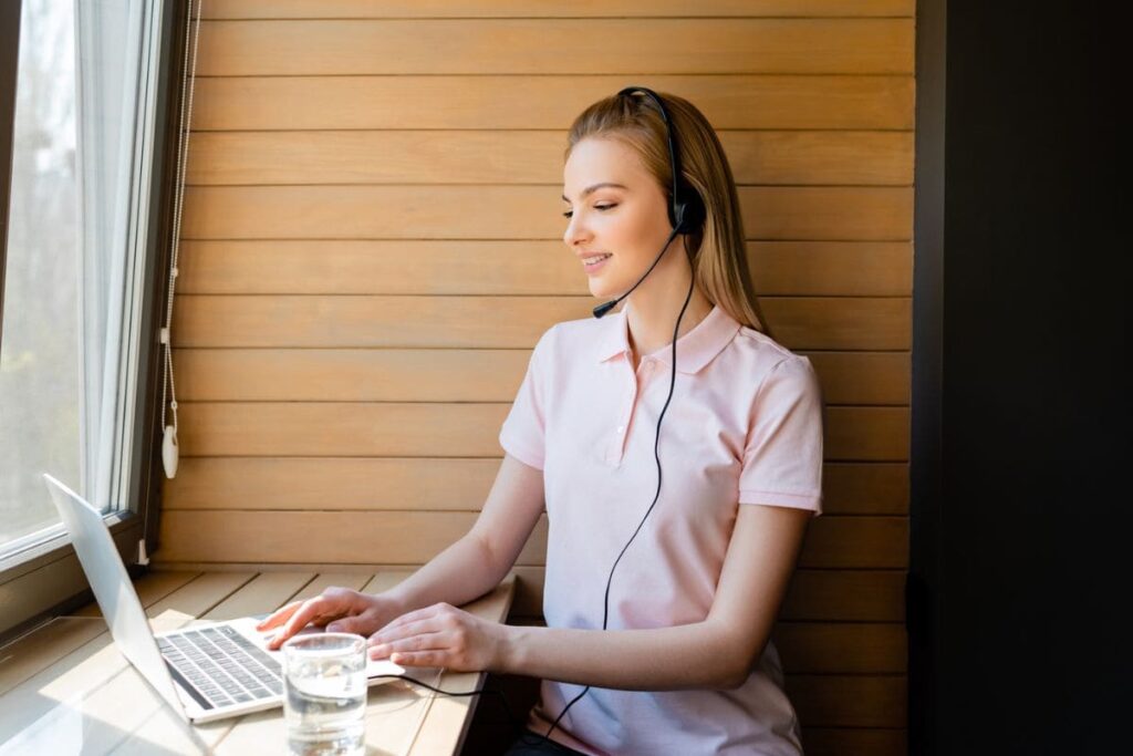 A work at home appointment setter working on a laptop with a headset.