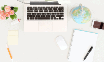 Desk with laptop, flowers, notebook, and a globe