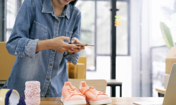 Young woman taking a photo of shoes she is selling online