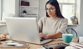 Young woman wearing glasses working on laptop in a remote HR job