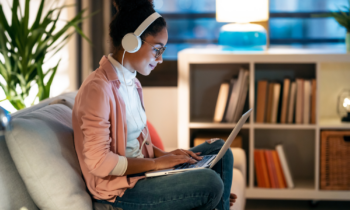 Young woman wearing headphones working her remote night shift job on the sofa