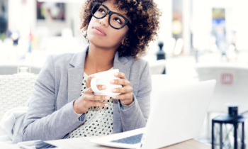 Young woman wearing glasses and drinking coffee wondering where to find legit work from home jobs with no startup fees